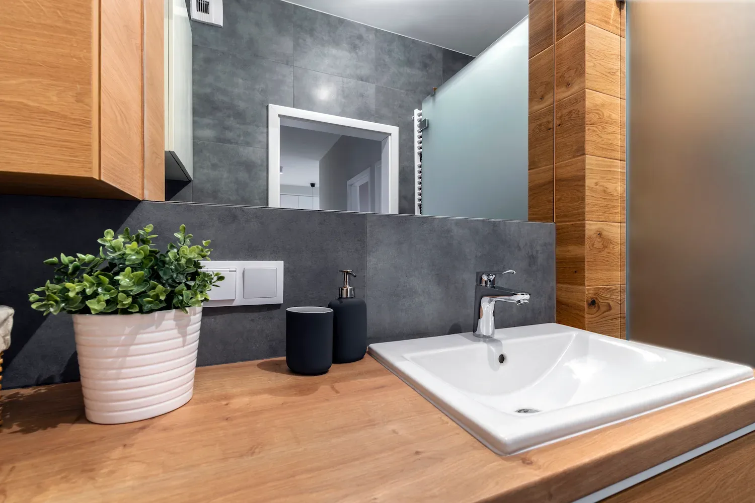 Close-up of timber bathroom vanity and grey tiling